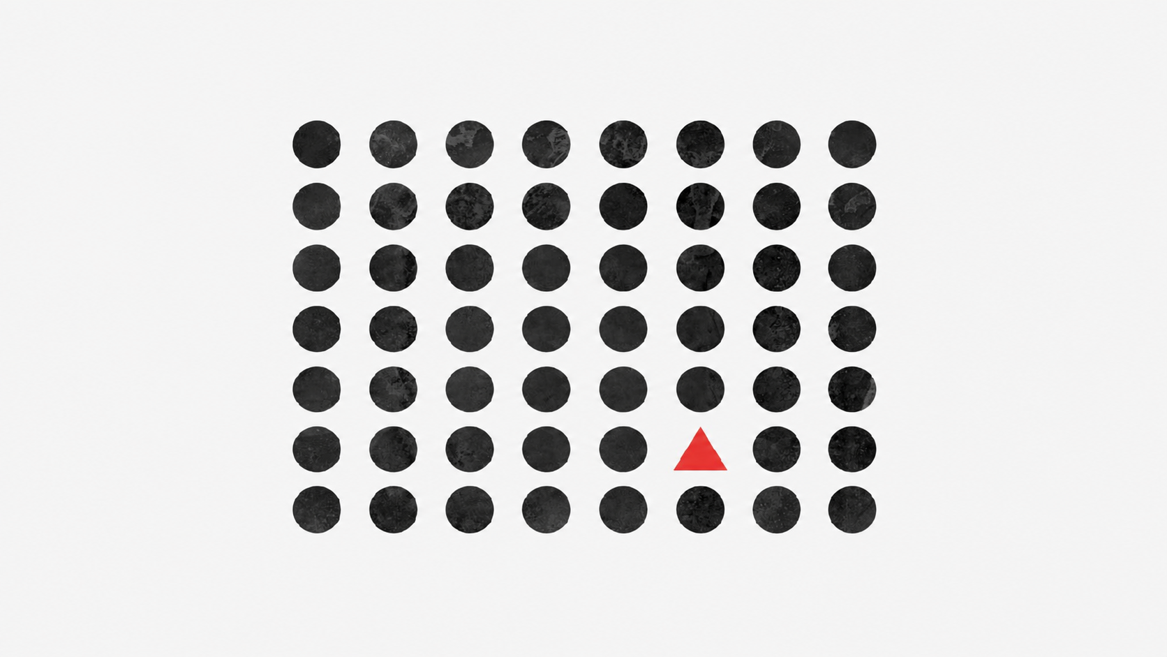 A grid of black dots with a single red triangle standing out among them