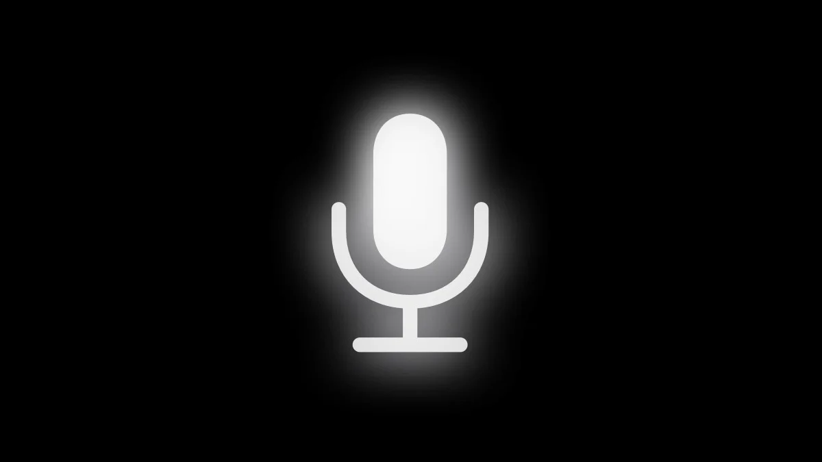 Apple's glowing white dictation microphone on a black background