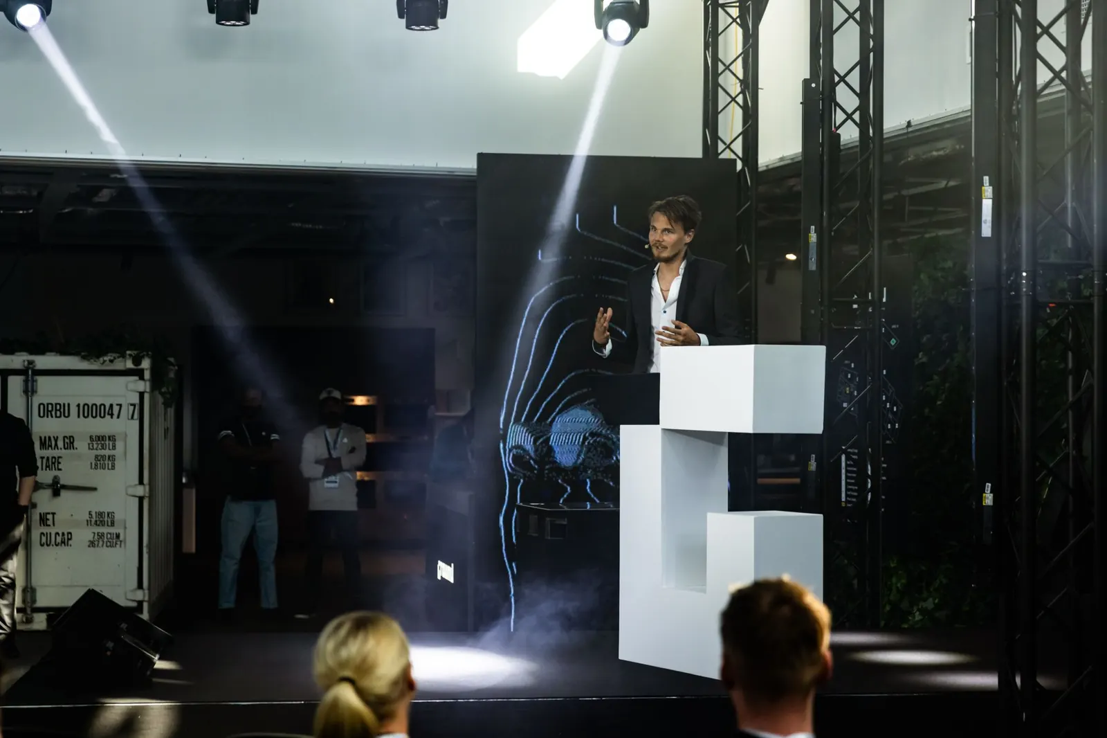 David hosting from the podium under the stage lights