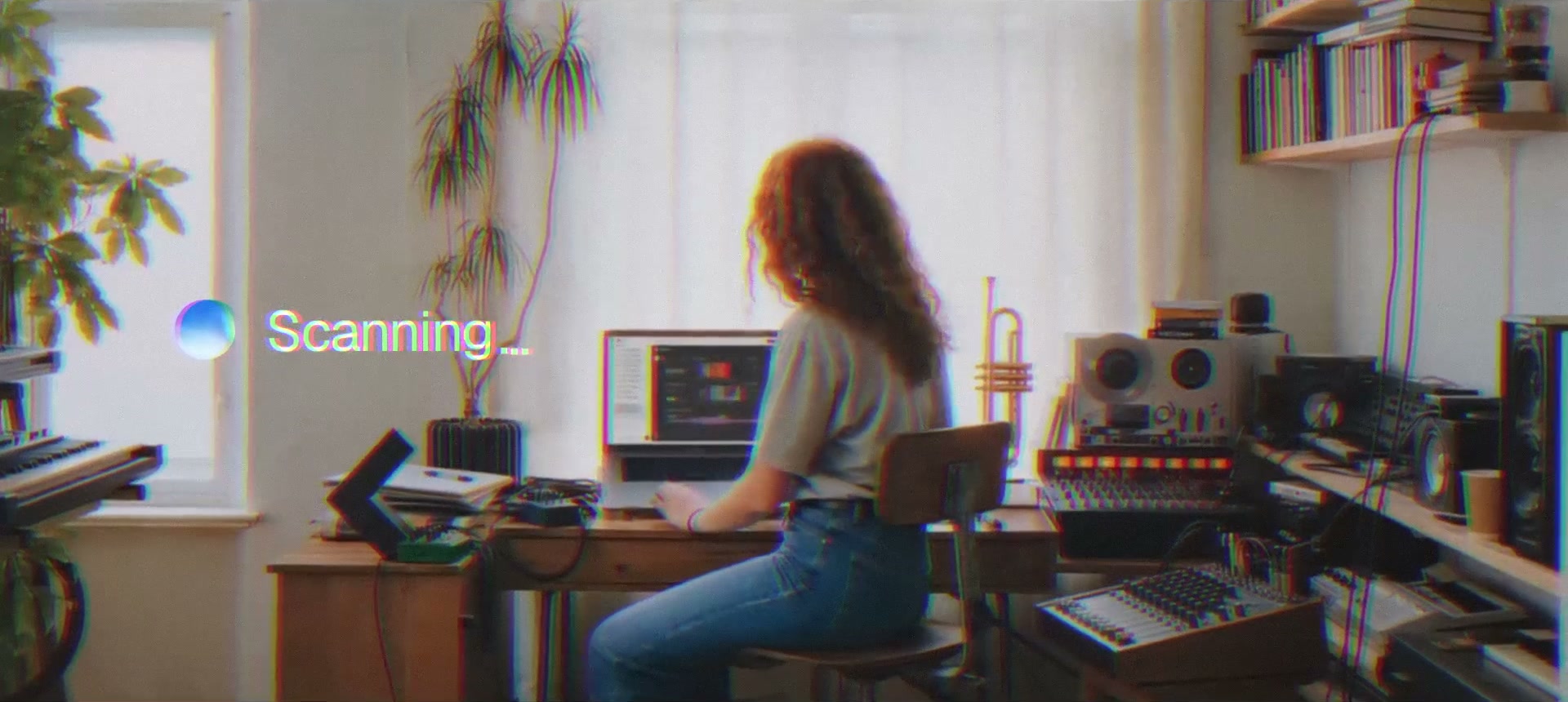 A woman at a desk in a home studio while Incredible works on her laptop